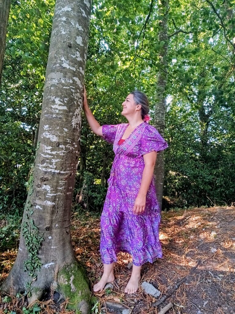 Mélanie Julien en robe violette, la main posée sur un arbre
